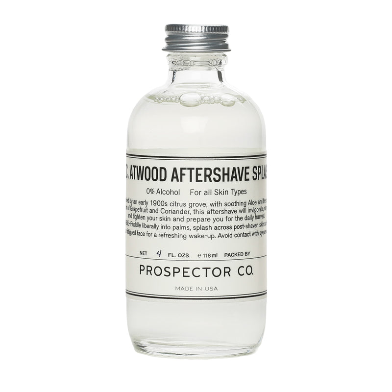 A clear glass bottle of product with silver cap and cream-colored ingredients label.