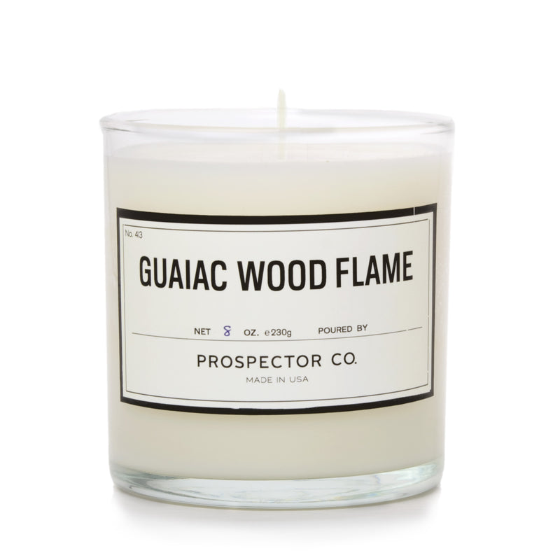 A glass candle container with wax, wick, and cream-colored label.