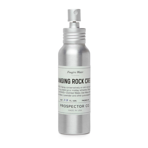 A metal spray bottle of product with silver cap and mint-colored ingredients label.